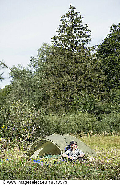 Teenage boy sitting near his camp tent in forest  Bavaria  Germany