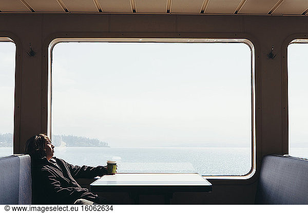 Teenage boy sitting on ferry looking out of a window