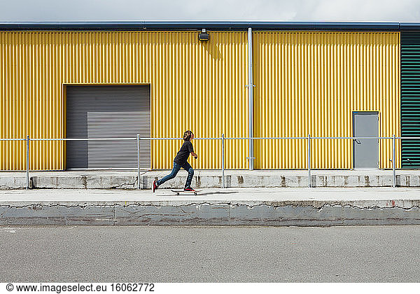 Teenage boy skateboarding in front of industrial warehouse loading zone