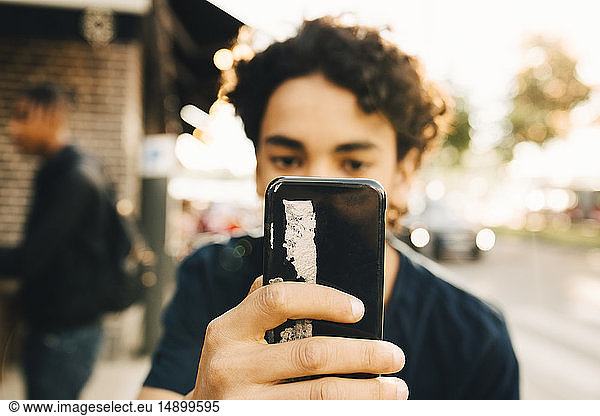 Teenage boy using mobile phone in city