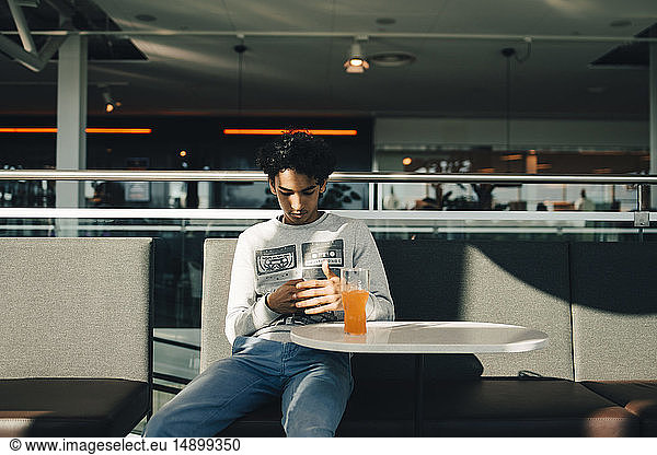 Teenage boy using mobile phone while sitting in restaurant