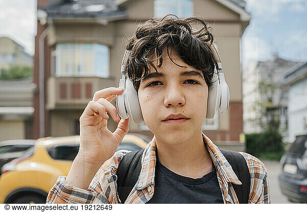 Teenage boy wearing headphones in city