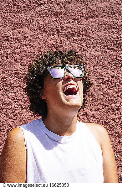 Teenage boy wearing sunglasses with mouth open against brown wall