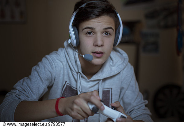 Teenage boy with headset playing video game