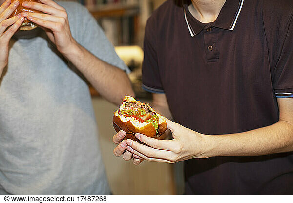 Teenage boys eating hamburgers