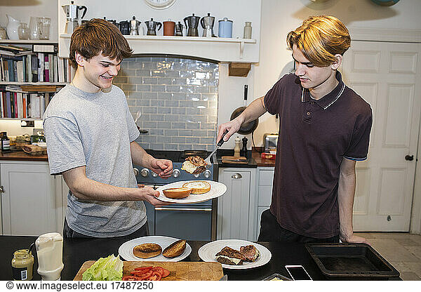 Teenage boys making hamburgers in kitchen