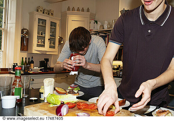 Teenage boys making hamburgers in kitchen