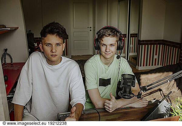 Teenage boys podcasting and showing thumbs up sign at home