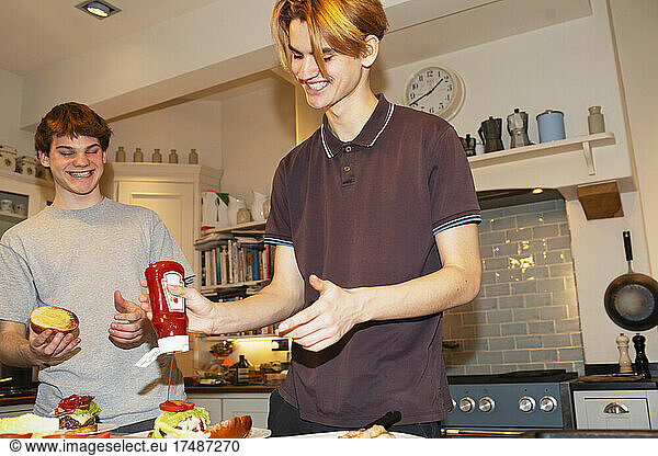Teenage boys preparing hamburgers in kitchen