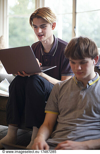 Teenage boys with laptops studying at home