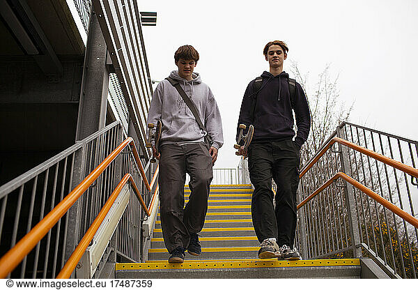 Teenage boys with skateboards descending urban staircase