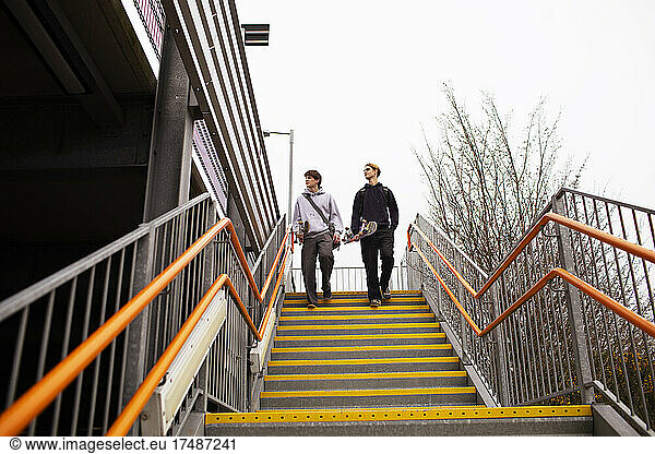 Teenage boys with skateboards descending urban steps