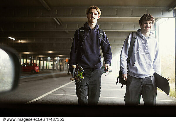 Teenage boys with skateboards in car park