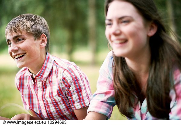 Teenage brother and sister laughing in woodland