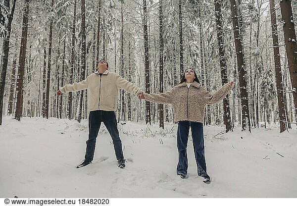 Teenage couple holding hands standing in snowy forest