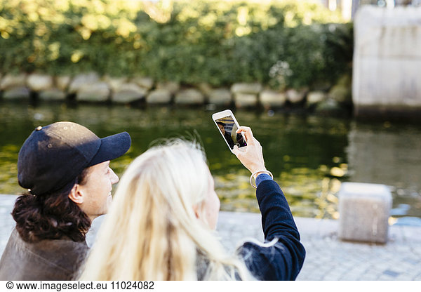 Teenage friends clicking selfie with smart phone outdoors