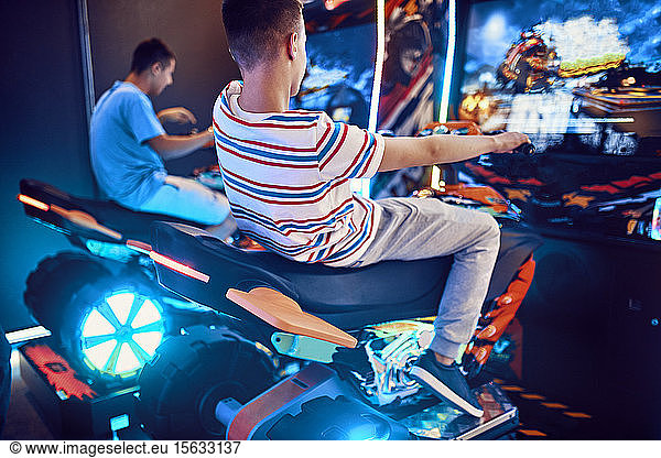 Teenage friends playing with a driving simulator in an amusement arcade