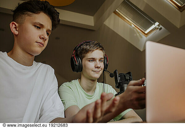 Teenage friends podcasting and gesturing in front of laptop