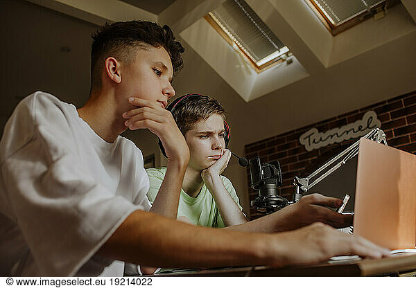 Teenage friends podcasting in front of laptop at home