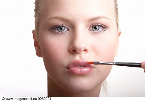 Teenage girl applying lip gloss