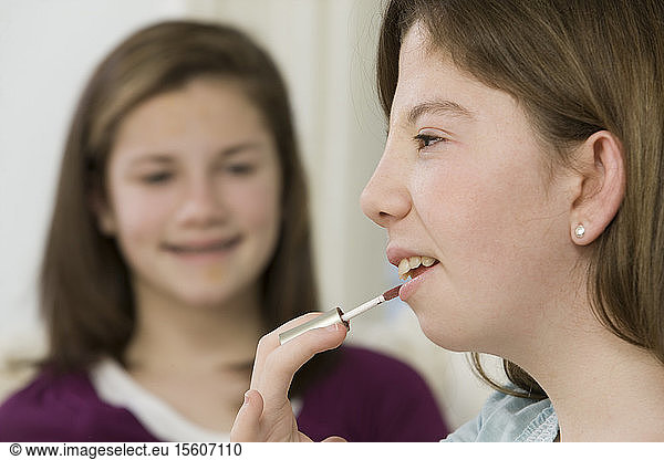Teenage girl applying lip gloss  Teenage girl with birth defect talking on a mobile phone