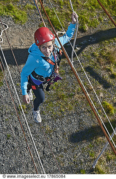 teenage girl balance on rope at high rope playground in Iceland