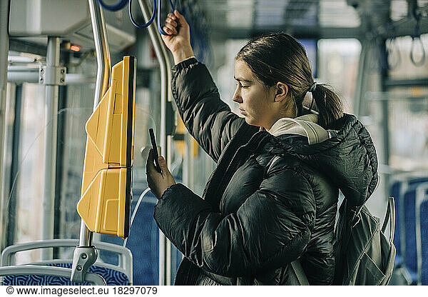 Teenage girl buying ticket through smart phone in tram