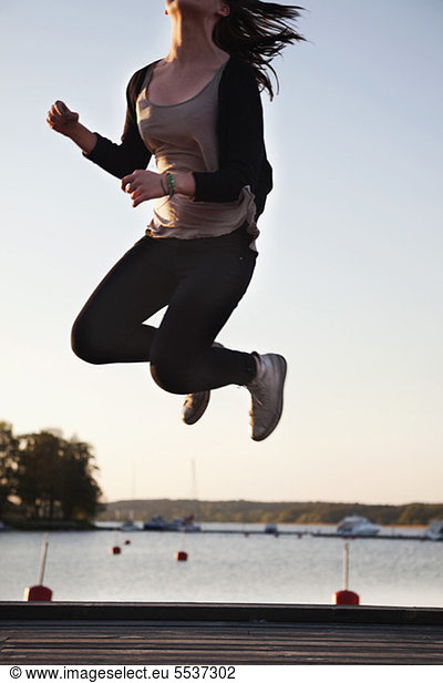 Teenage girl enjoying freedom by jumping on pier