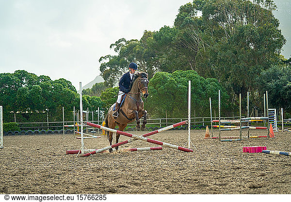 Teenage girl equestrian jumping in paddock