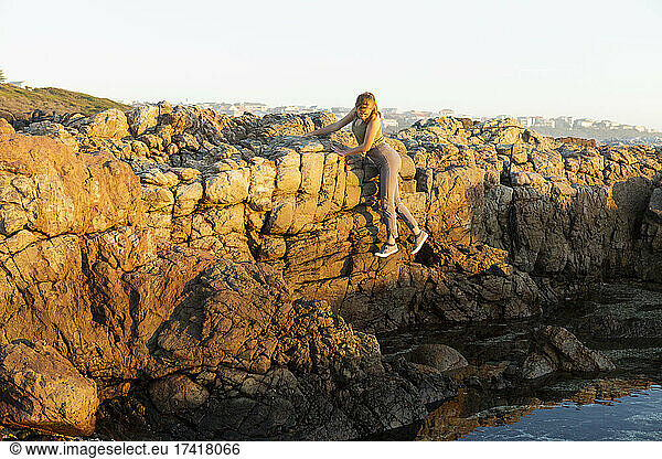 Teenage girl exploring the jagged rocks on the De Kelders coastline