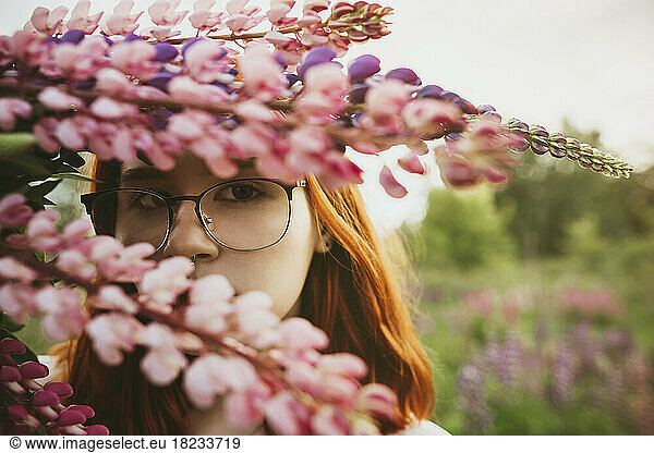 Teenage girl holding bouquet of lupin flowers over face