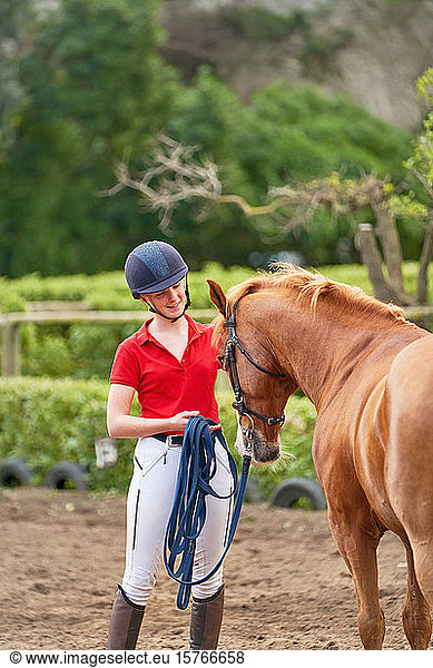 Teenage girl in equestrian helmet training horse