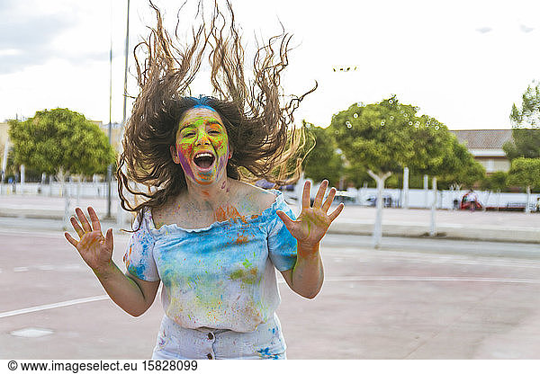 teenage girl jumps and screams for joy  playing with colored powders a