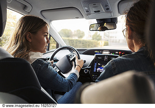 Teenage girl learning to drive from mother during weekend