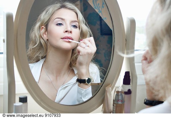 Teenage girl looking in mirror  applying make-up