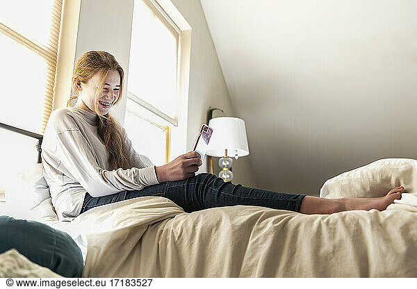teenage girl lying on her bed using her smart phone