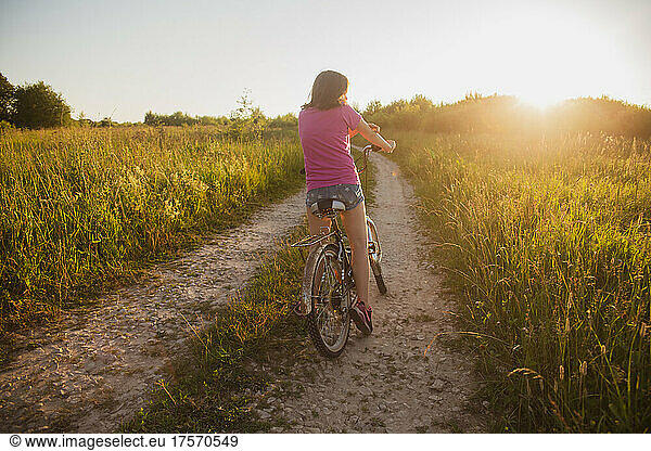 Teenage girl on an old bike in the field