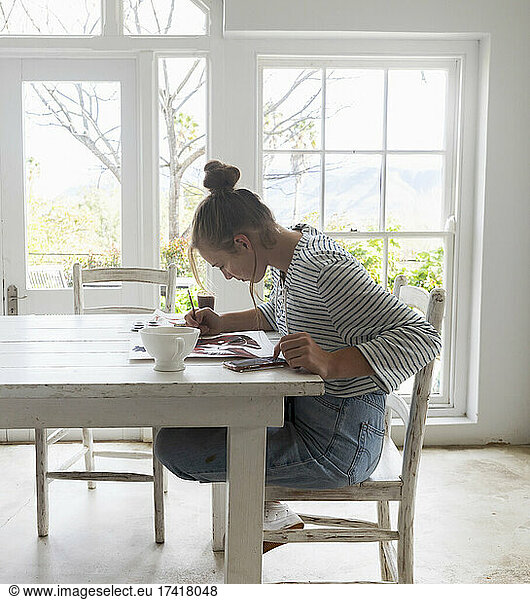 Teenage girl painting with watercolours in a light filled room