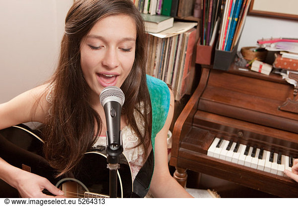 Teenage girl playing guitar and singing