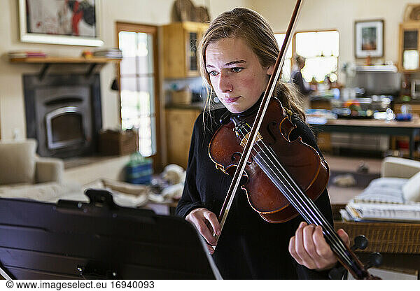 Teenage girl practicing violin at home