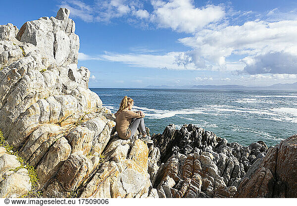 Teenage girl sitting on rocks overlooking the Atlantic ocean and coastline