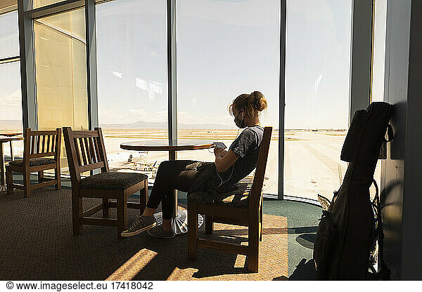 Teenage girl sitting waiting in an airport lounge  on her smart phone  Botswana.