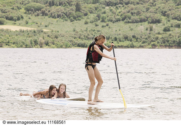 Teenage girl stand up paddle surfing on a lake.
