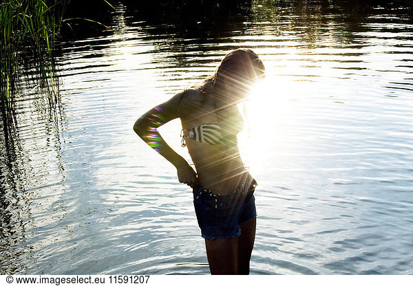 Teenage girl standing in sunlit river