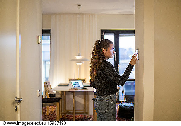 Teenage girl using digital tablet mounted on wall at home