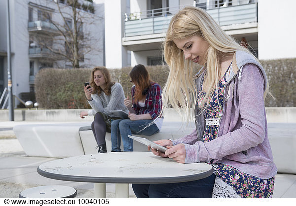 Teenage girl using digital tablet with her friends using technology in background  Munich  Bavaria  Germany