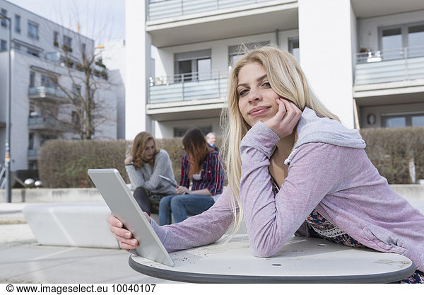 Teenage girl using digital tablet with her friends using technology in background  Munich  Bavaria  Germany