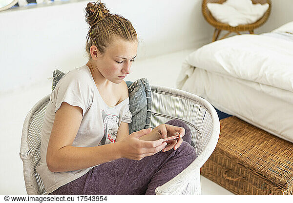 Teenage girl using smart phone in her bedroom