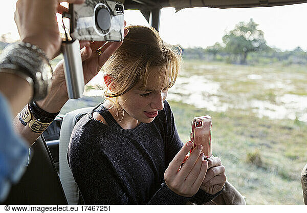 Teenage girl using smart phone to take a picture during a safari jeep drive.