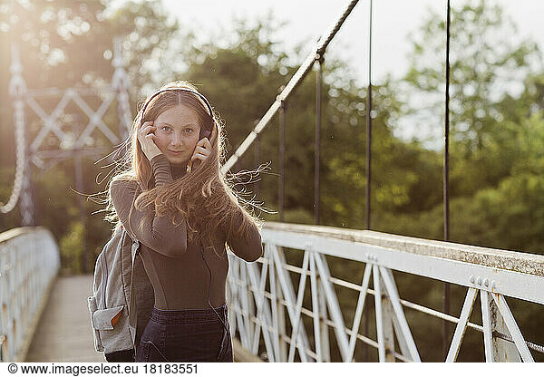 Teenage girl using smartphone and listening music on a bridge